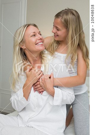 Mother and daughter looking at each in bed 10048638