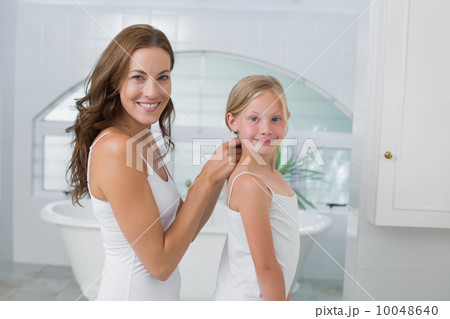Woman braiding cute little girl's hair in bathroom 10048640