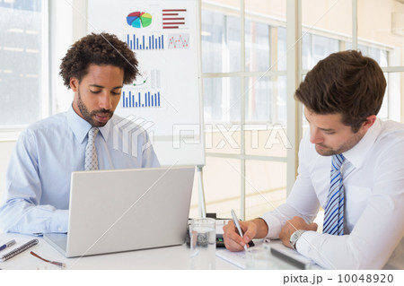 Concentrated businessmen with graph board in background Concentrated businessmen with graph board in background 10048920