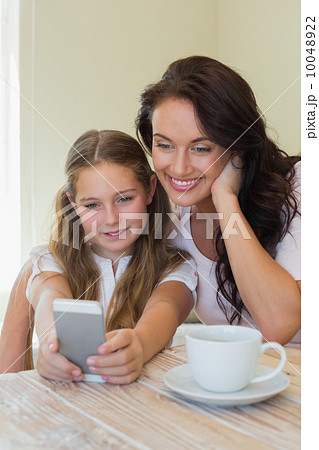 Daughter with mother taking self portrait through mobile phone 10048922