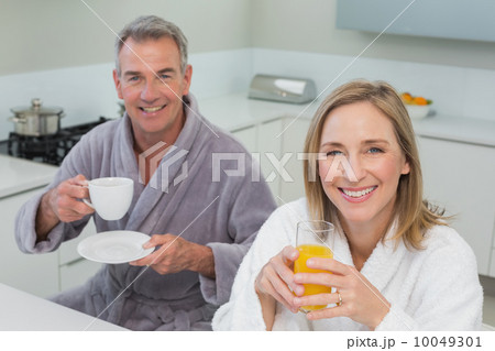 Smiling couple with orange juice and coffee in kitchen 10049301