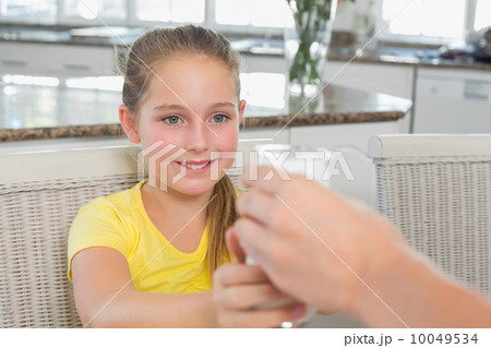 Girl receiving glass of milk from mother Girl receiving glass of milk from mother 10049534