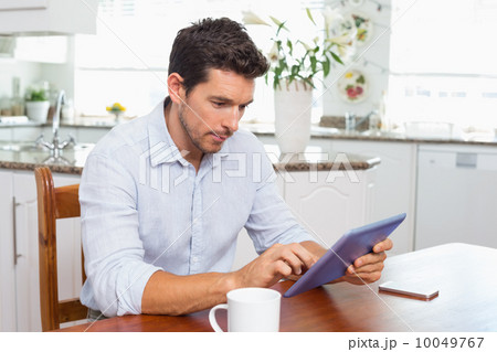 Concentrated man using digital tablet in kitchen 10049767