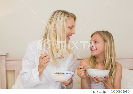 Mother and daughter having cereals in bedroom Mother and daughter having cereals in bedroom 10050640