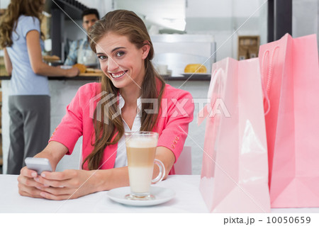 Smiling woman using mobile phone in coffee shop 10050659
