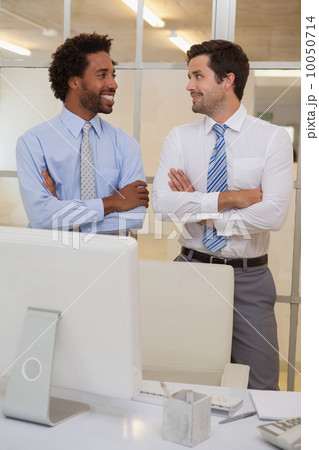 Two smiling businessmen with arms crossed in office Two smiling businessmen with arms crossed in office 10050714