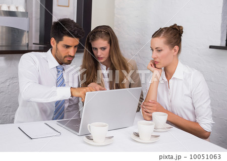 Business people using laptop together at office desk Business people using laptop together at office desk 10051063