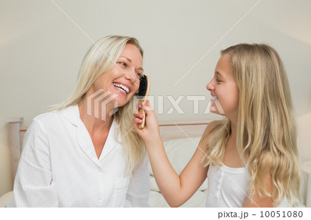 Girl brushing hair of mother in bedroom Girl brushing hair of mother in bedroom 10051080