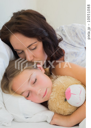 Mother kissing sleeping daughter in bed Mother kissing sleeping daughter in bed 10051088