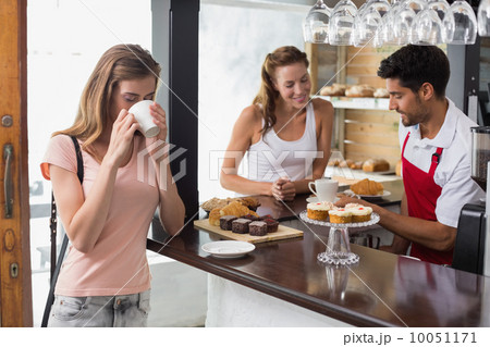 Woman drinking coffee with friend and male barista in coffee sho Woman drinking coffee with friend and male barista in coffee sho 10051171