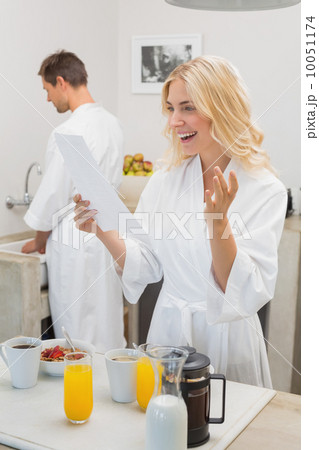 Smiling woman looking at document with man in kitchen Smiling woman looking at document with man in kitchen 10051174