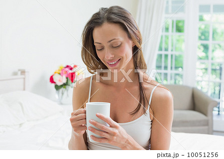 Relaxed woman with coffee cup sitting in bed Relaxed woman with coffee cup sitting in bed 10051256