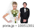Bride smelling flowers while groom standing in background 10051301