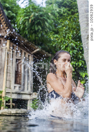 A young brunette caucasian women swinging on the rope, falling into a  pond in the countryside 10062939
