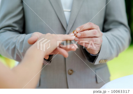 Groom putting a ring on bride's finger 10063317