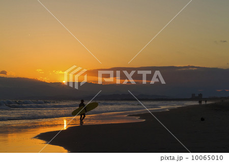 美しい夕日の中でサーフィンを終えたサーファー 美しい夕日の中でサーフィンを終えたサーファー 10065010