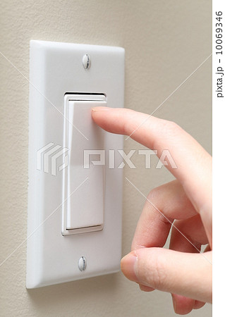 Woman hand turning on the light with a wall switch 10069346
