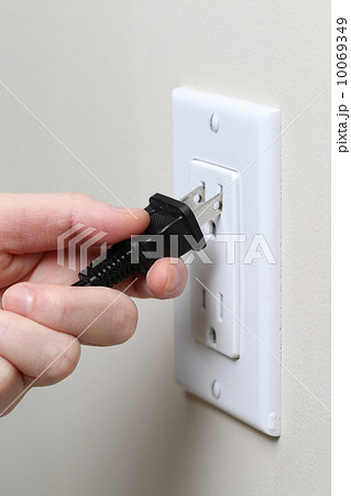 Hand inserting an electrical plug into a wall socket 10069349