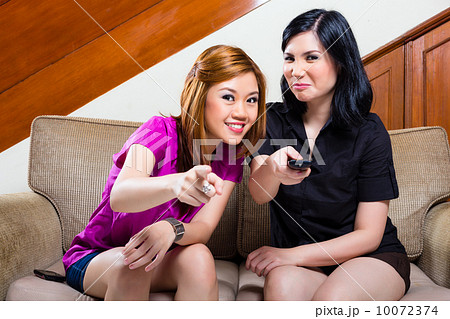 Two asian girls at home watching TV 10072374