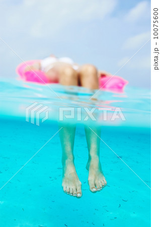 Woman relaxing on inflatable mattress, view from underwater Woman relaxing on inflatable mattress, view from underwater 10075600