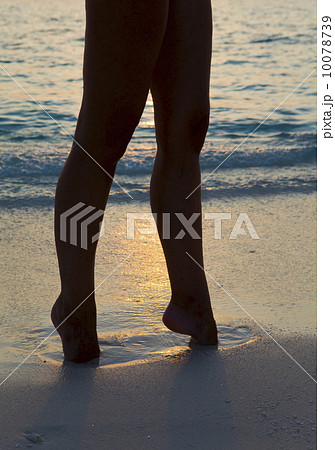 Silhouette of female legs on sand at ocean 10078739