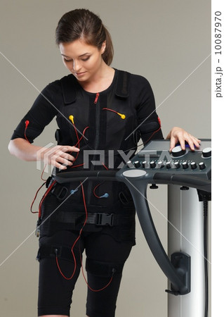 Young woman in training costume near Electro Muscular Stimulation EMS machine Young woman in training costume near Electro Muscular Stimulation EMS machine 10087970
