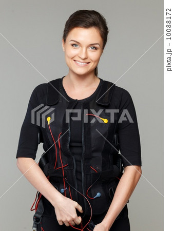 Young woman putting on Electro Muscular Stimulation EMS exercise training costume Young woman putting on Electro Muscular Stimulation EMS exercise training costume 10088172