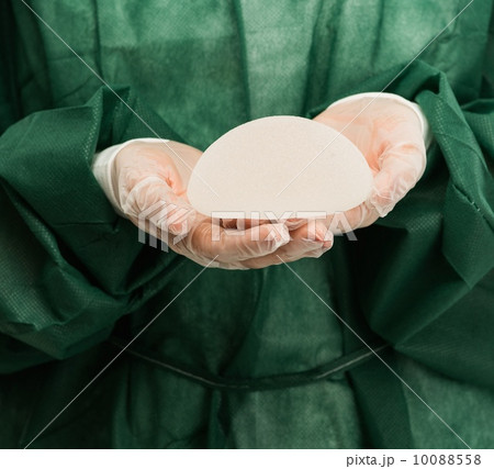 Plastic surgeon hands holding silicon breast implants Plastic surgeon hands holding silicon breast implants 10088558