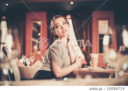 Beautiful young woman with cup of coffee alone in a restaurant Beautiful young woman with cup of coffee alone in a restaurant 10088724