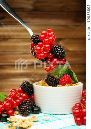 Healthy breakfast with muesli and berries on tablecloth in wooden rural interior 10088805