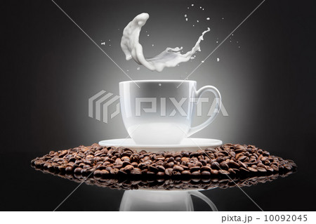 white cup with coffee beans and milk splash on black 10092045