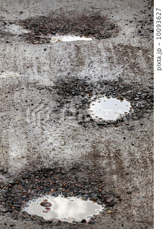 Damaged wet road with holes 10093627