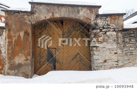 Stone wall of an ancient building with weathered wooden gate and snowdrift.Tallinn, Estonia Stone wall of an ancient building with weathered wooden gate and snowdrift.Tallinn, Estonia 10093948