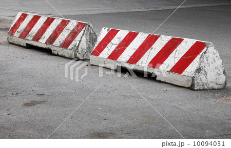 Red and white striped concrete road barriers lying on the pavement Red and white striped concrete road barriers lying on the pavement 10094031