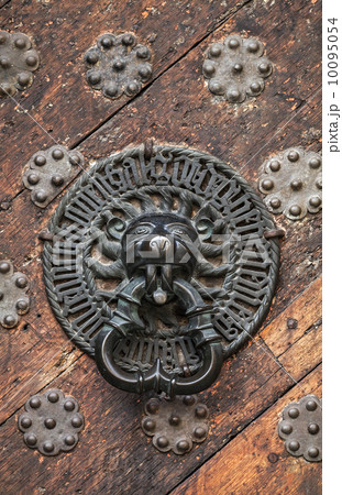 Ancient weathered door fragment with metal lion head handle. Old Ancient weathered door fragment with metal lion head handle. Old 10095054