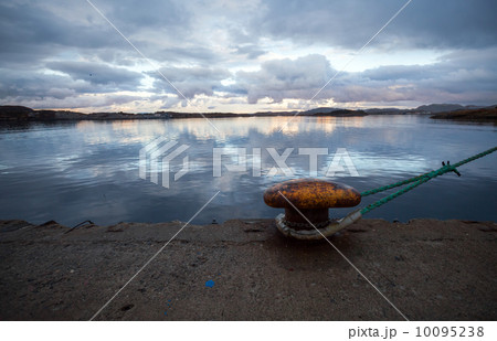 Old rusted yellow mooring bollard with rope at night Old rusted yellow mooring bollard with rope at night 10095238