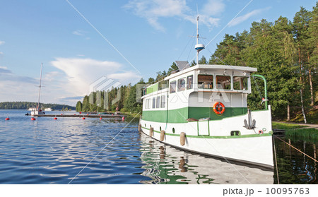 Small white pleasure boat moored on Saimaa lake in Finland 10095763