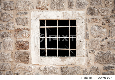 Ancient stone prison wall with metal window bars 10096357