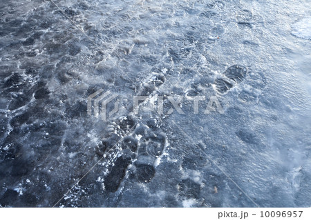 Pedestrians footprints in road blue ice. Street sleet background 10096957