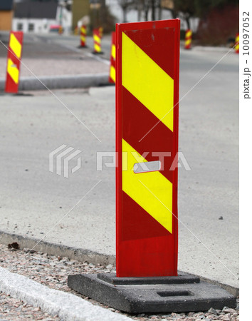 Vertical red and yellow striped caution road sign. Road under co 10097052