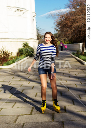 Pretty teenage girl rollerskating in park Pretty teenage girl rollerskating in park 10110529