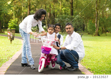 indian family teaching their kids cycling in the outdoor park 10122027