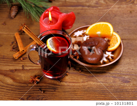 Mulled wine in glass with cinnamon stick, candle and sweets Mulled wine in glass with cinnamon stick, candle and sweets 10131801