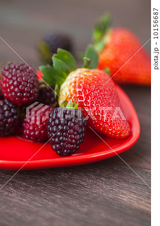 red juicy strawberry and blackberry in red plate on a wooden sur red juicy strawberry and blackberry in red plate on a wooden sur 10156687
