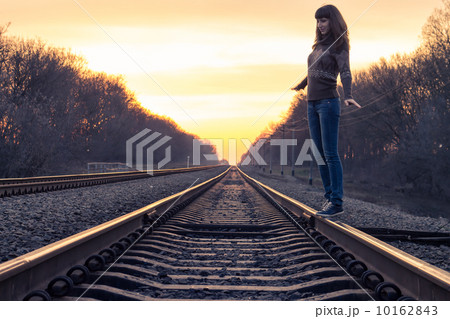 Young adult girl balance on railroad in sunset beams Young adult girl balance on railroad in sunset beams 10162843