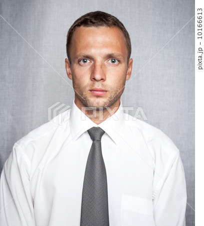 Young serious man in white shirt with tie over gray background. Studio portrait 10166613