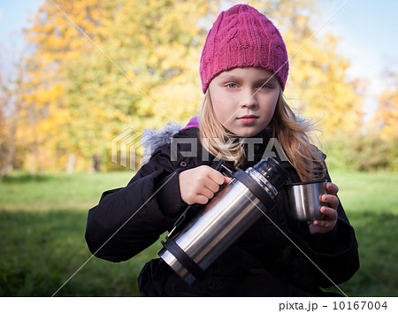 little beautiful blond girl pours tea from a thermos in autumnal park 10167004