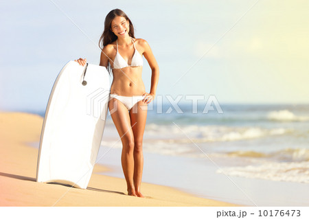 Surfer bikini woman on beach smiling with surfboard 10176473
