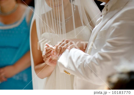 Bride putting the ring on groom's finger 10183770