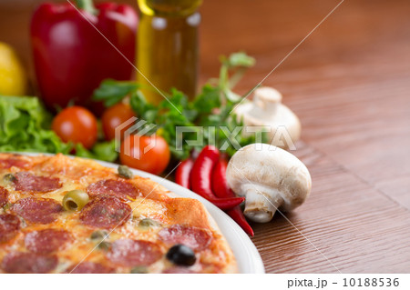 Salami pizza on table with vegetables and empty room 10188536